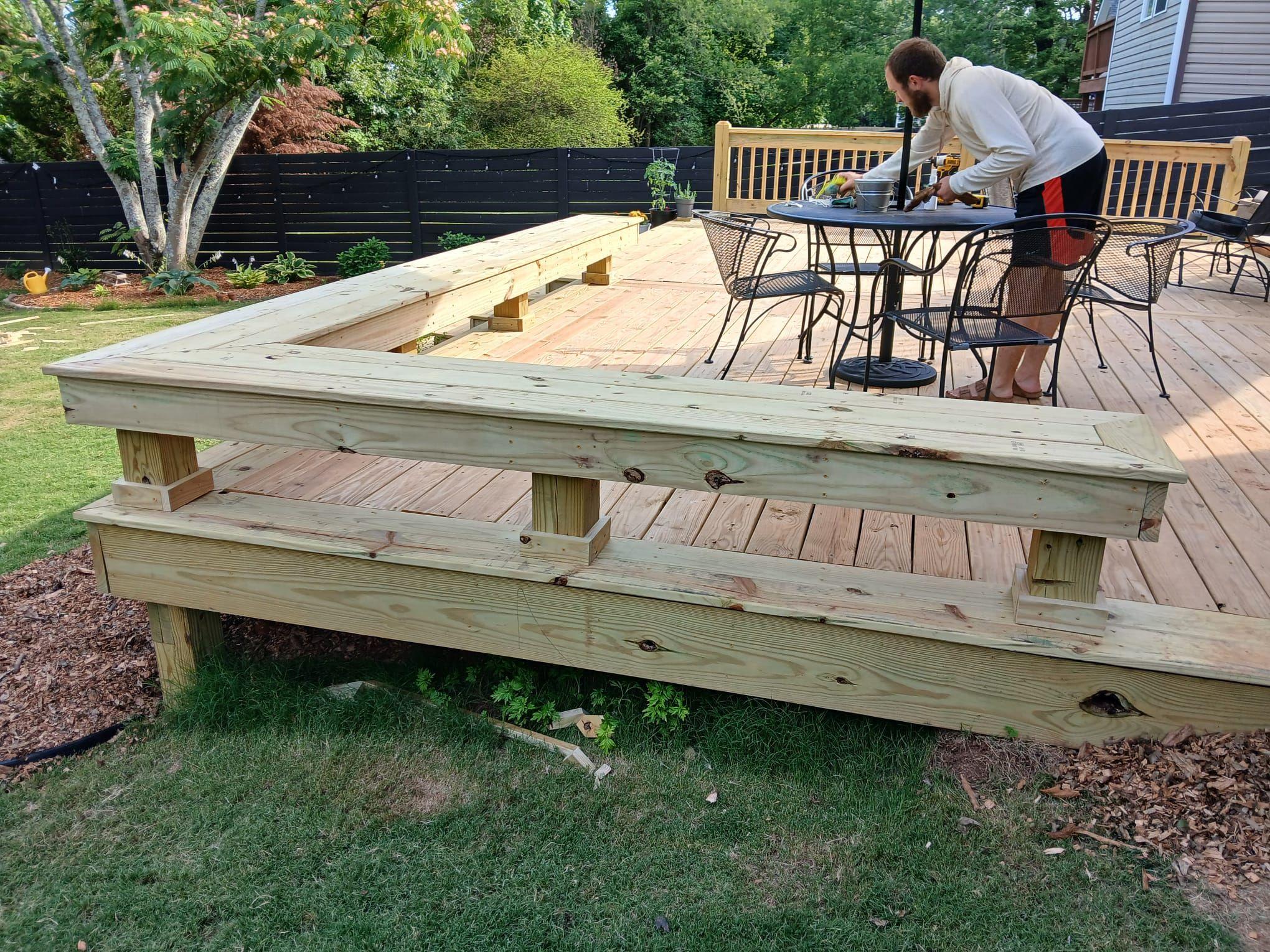 Patio table and chairs on a pine deck wrapped by a built-in bench