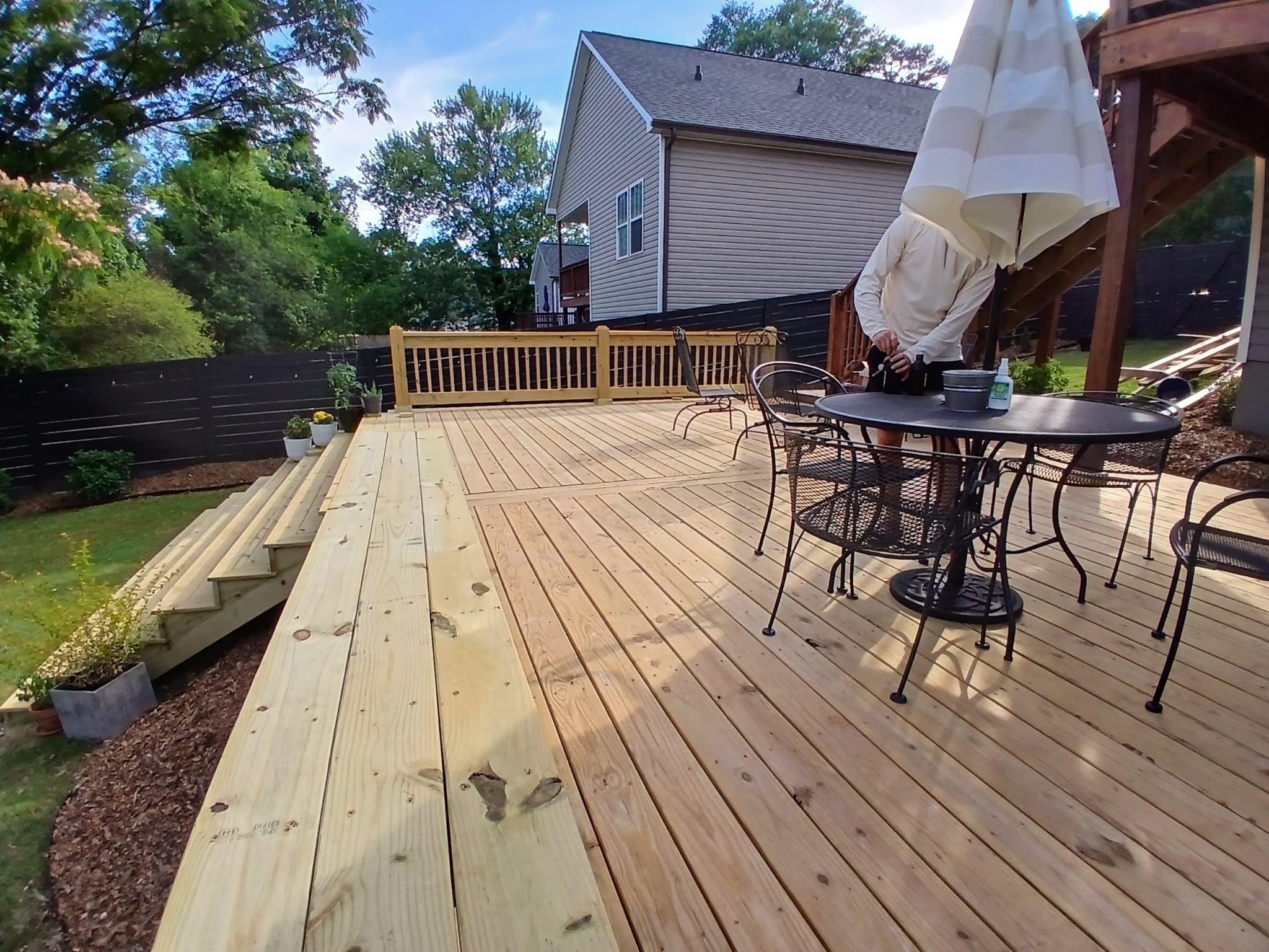 Long view across new deck boards toward a patio table and umbrella