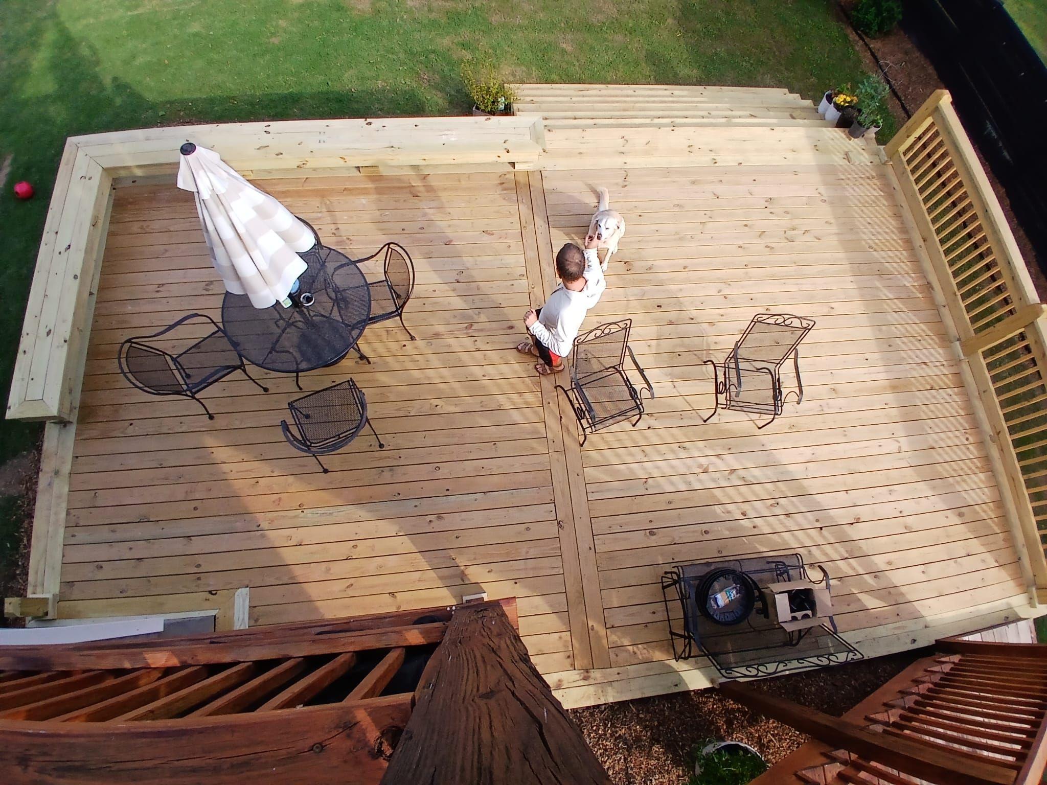Overhead view of a finished pine deck with a patio table, umbrella and chairs